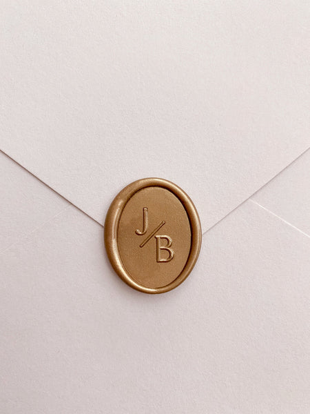 Modern monogram oval wax seal in gold on beige card stock envelope