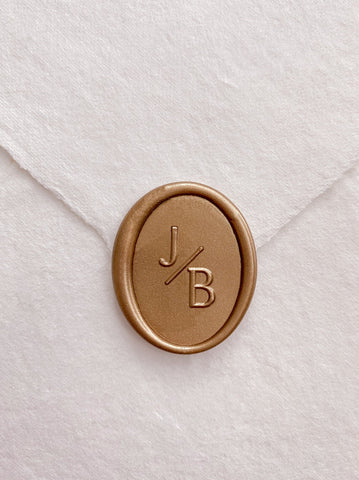 Modern monogram oval wax seal in gold on handmade paper envelope
