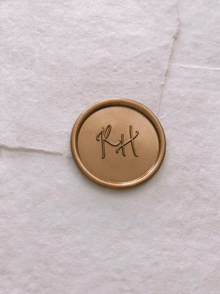 Calligraphy script monogram round wax seal in gold on handmade paper envelope_side angle