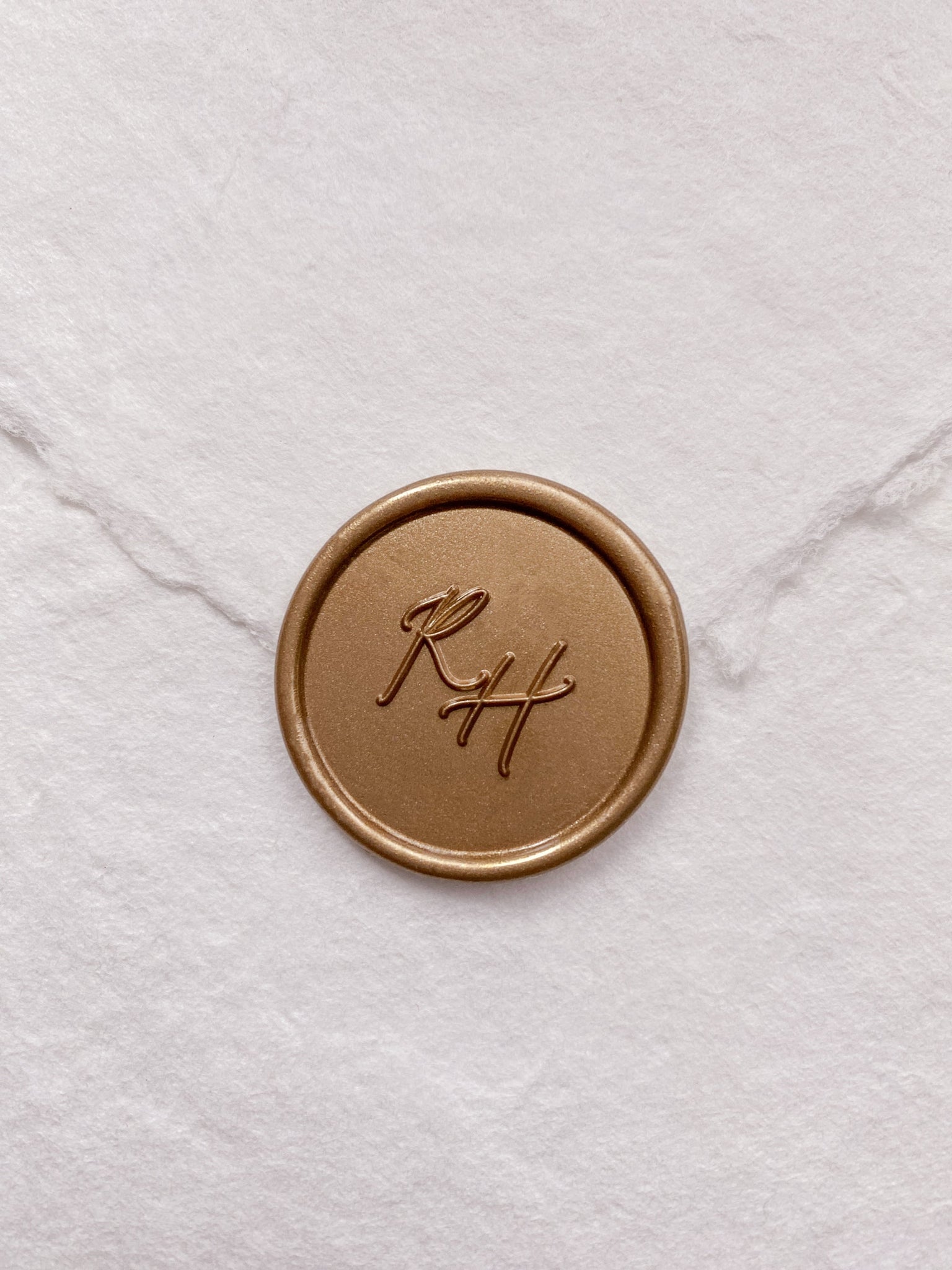 Calligraphy script monogram round wax seal in gold on handmade paper envelope