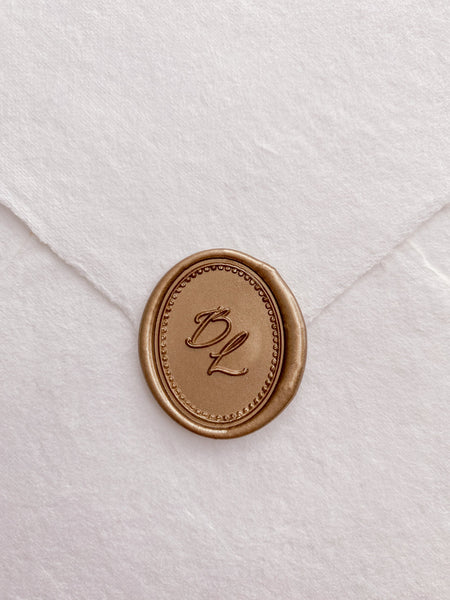 Border design oval monogram wax seal in gold on handmade paper envelope