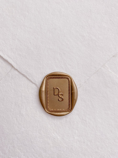 Rectangular border monogram gold wax seal on handmade paper envelope