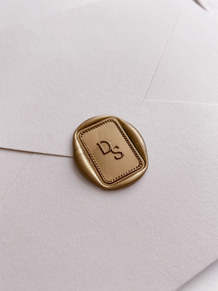 Monogram with border design rectangular wax seal in gold on beige envelope