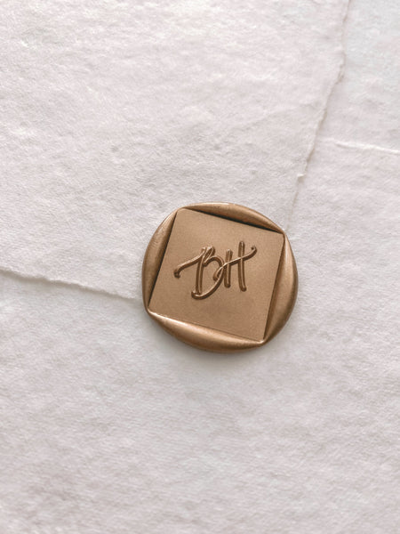 Calligraphy script monogram diamond shaped wax seal in gold on handmade paper envelope_side angle