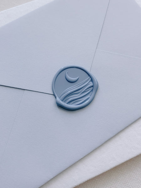 3D engraved moon and ocean wax seal in dusty blue on dusty blue envelope_closeup side angle