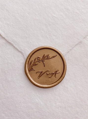 Floral branch monogram wax seal in gold with calligraphy script initials on handmade paper envelope