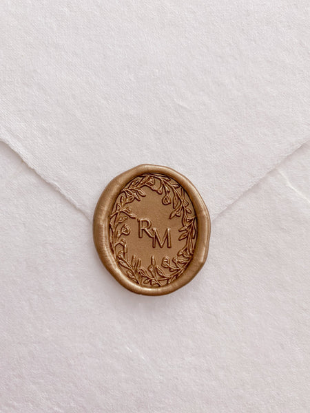Oval floral crown monogram wax seal in gold on handmade paper envelope
