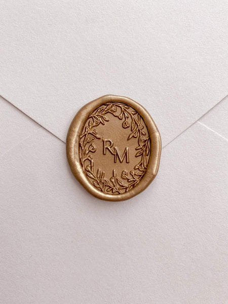 Oval floral crown monogram wax seal in gold on beige card stock envelope 