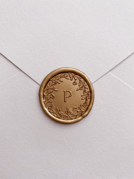 Floral crown single-initial round wax seal in gold on card stock envelope