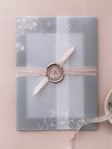 Floral crown single-initial round wax seal in color Mocha on vellum wrapped wedding invitation with blush silk ribbon