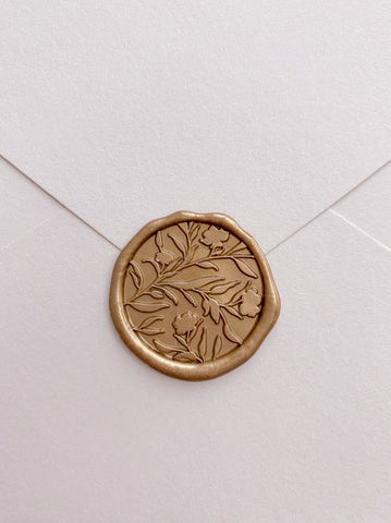 Floral silhouette wax seal in gold_front angle on beige envelope