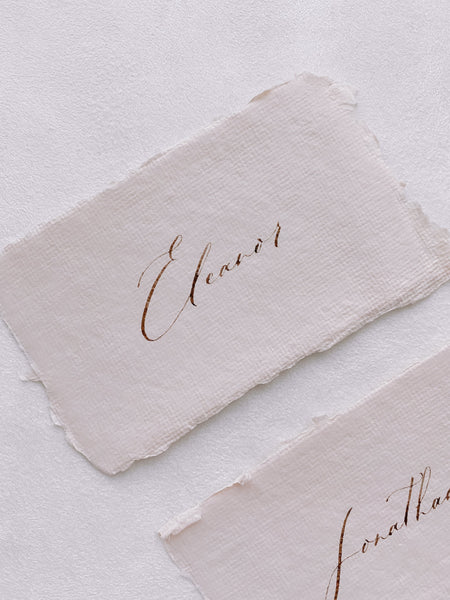 handmade paper place cards in light cream color hand lettered in modern calligraphy in brown ink_close up side angle
