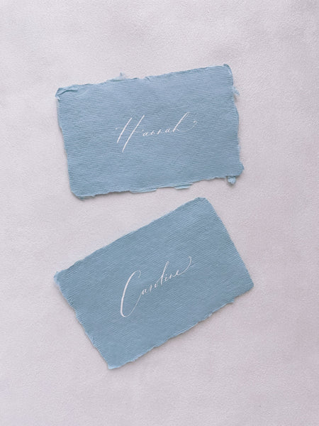 handmade paper place cards in sky color hand lettered in modern calligraphy in white ink_front angle
