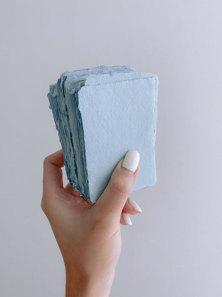 a stack of handmade paper place cards in sky color