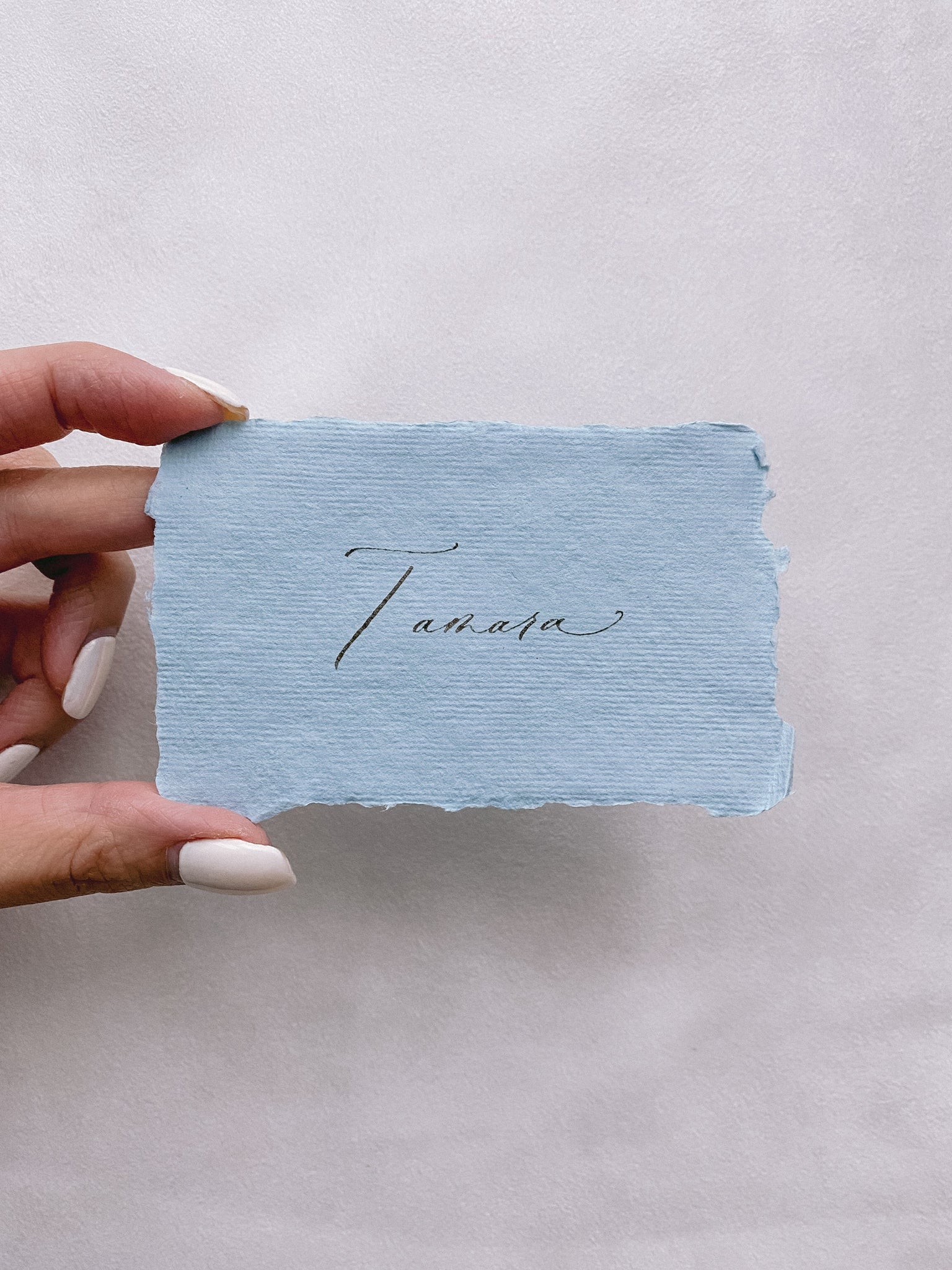 handmade paper place card in sky color hand lettered in modern calligraphy in black ink