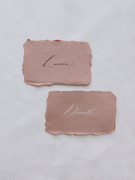 handmade paper place cards in terracotta color hand lettered in modern calligraphy in black and white ink_front angle