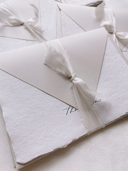 Handmade thank you cards with silk ribbon tied around light gray paper envelope_closeup side angle