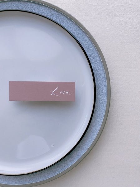 slim place card in rose color hand lettered in modern calligraphy in white ink