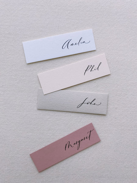 slim place cards hand lettered in modern calligraphy, white card with black ink, light blush with black ink, beige with black ink, rose with black ink_front angle