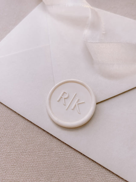 Modern font monogram round wax seal off white on paper envelope_side angle