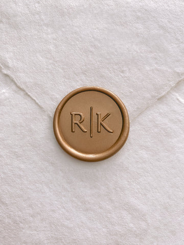 Modern typeface monogram wax seal in gold on handmade paper envelope_front angle