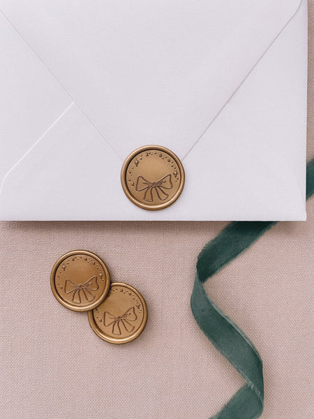 Ribbon bow gold wax seals on white envelope