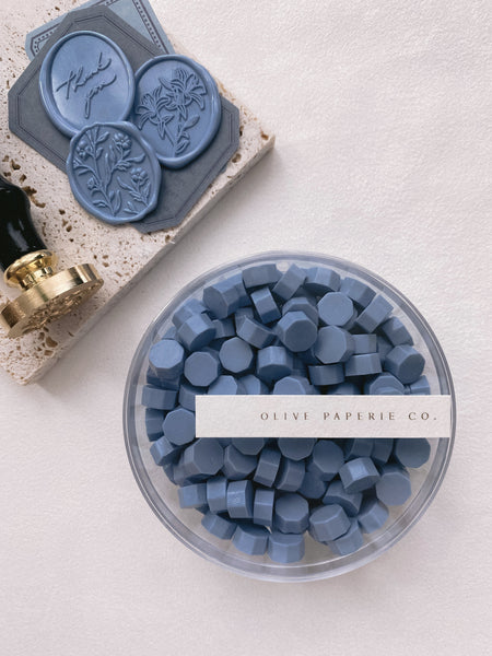 a box of dusty blue sealing wax beads with an oval thank you wax seal, scarlette 3d floral wax seal and lily oval wax seal in dusty blue color
