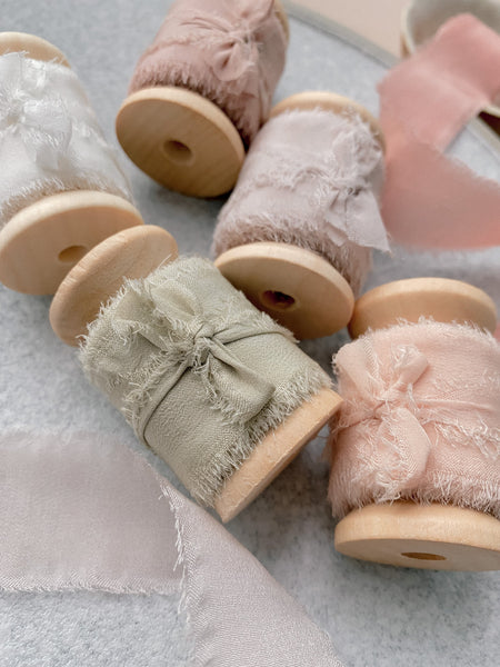 1 inch raw edge silk ribbon on wooden spools in color Soft White, Nude Grey, Dusty Blush, and Cream White