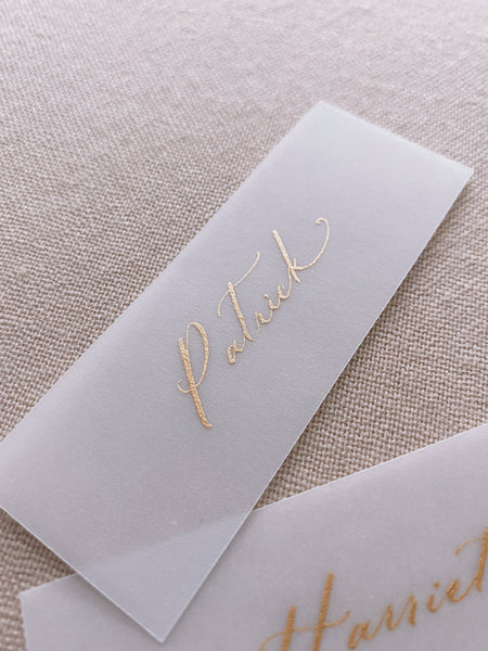 slim vellum place card in hand lettered calligraphy in gold ink_closeup side angle