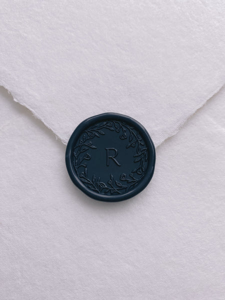 Floral crown single initial wax seal in deep blue color on handmade paper envelope_front angle